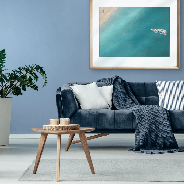 Wall Mounted Gold framed Coastal Wall Art featuring a dark to light aqua ocean and a single white boat drifting towards the shoreline.