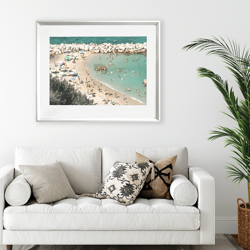 Coastal living room with Silver framed Coastal Wall Art Vacanza 02 – Studio Collection, featuring the European beach coastline with holiday beach lovers bathing in the sunshine.