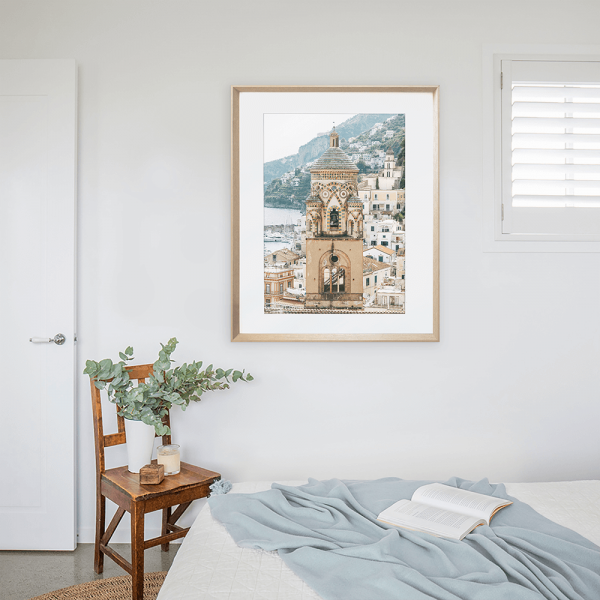 Gold framed Amalfi coast photos in Italy in a white painted bedroom