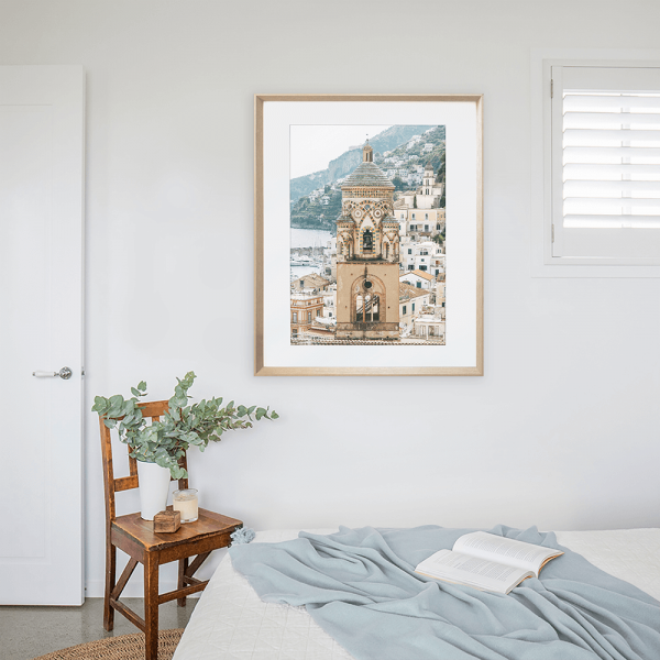 Gold framed Amalfi coast photo in Italy in a white painted bedroom