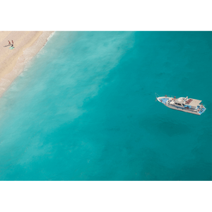 Unframed Coastal Wall Art featuring a dark to light aqua ocean and a single white boat drifting towards the shoreline.