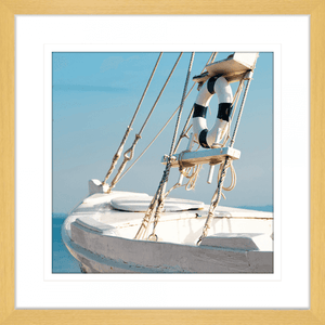 Gold framed Nautical Wall Art, featuring a single crisp white sailing ship floating on a pristine sky-blue ocean, against a pale blue skyline