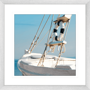 Silver framed Nautical Wall Art, featuring a single crisp white sailing ship floating on a pristine sky-blue ocean, against a pale blue skyline