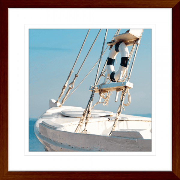 Wood framed Nautical Wall Art, featuring a single crisp white sailing ship floating on a pristine sky-blue ocean, against a pale blue skyline