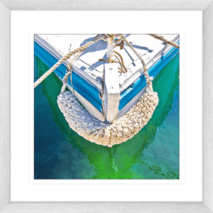 Silver Framed Nautical Wall Art, featuring the front section of white and light blue sailing ship floating on a pristine green ocean, moored with white nautical ropes.