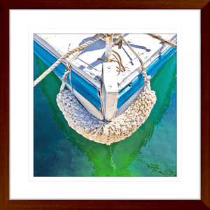 Wood Framed Nautical Wall Art, featuring the front section of white and light blue sailing ship floating on a pristine green ocean, moored with white nautical ropes.