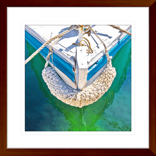 Wood Framed Nautical Wall Art, featuring the front section of white and light blue sailing ship floating on a pristine green ocean, moored with white nautical ropes.