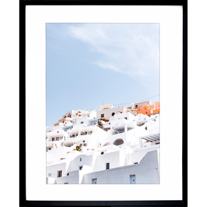 Black framed Greek Island Photo featuring iconic European white coastal homes under a soothing pale blue skyline.