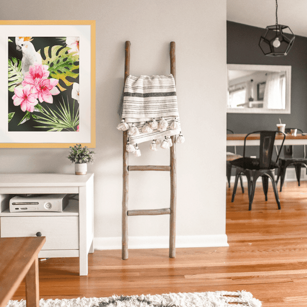 Gold framed Mounted Beach Art Australia, featuring a tropical scene with a white cockatoo perched within the green palm trees among striking pink flowers.