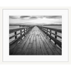 Black and white wall art features a long pier cascading into the deep ocean, with an array of white clouds overhead in a white frame