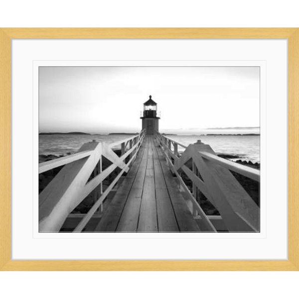 Black and white wall art features a single pier cascading into the deep ocean, culminating at a light house in an oak frame