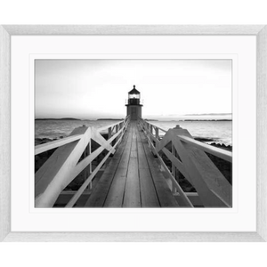 Black and white wall art features a single pier cascading into the deep ocean, culminating at a light house in a silver frame